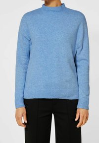 Helles blaues Strickpullover mit hohem Kragen, gerippten Bündchen und Saum. Weiche Textur, mit überschnittenen Schultern und lockerer Passform.