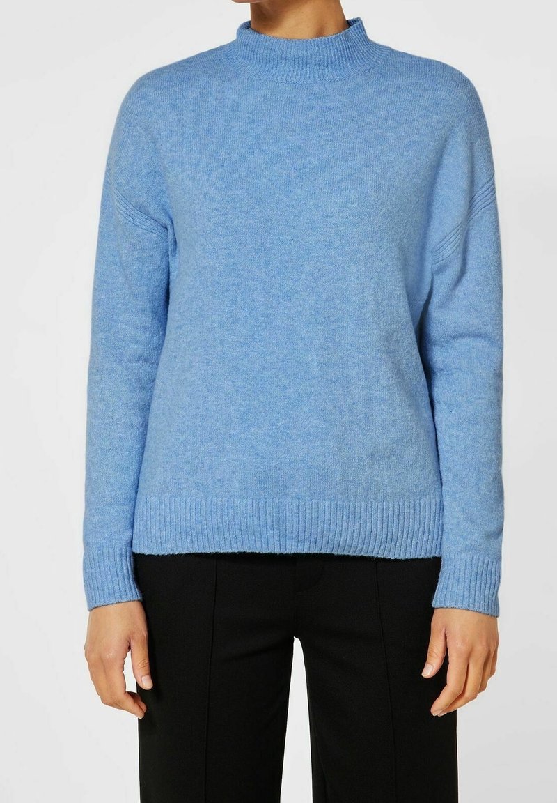 Helles blaues Strickpullover mit hohem Kragen, gerippten Bündchen und Saum. Weiche Textur, mit überschnittenen Schultern und lockerer Passform.