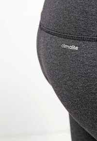 Svarta träningsleggings tillverkade av ett mjukt, elastiskt material; har en liten "climalite"-logotyp och en slät design på midjebandet.
