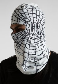 Balaclava blanca con patrón de telaraña negra, aberturas para los ojos y la boca, textura suave, tela ligera y detalle de botón en el lateral.