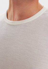 Kortærmet beige T-shirt med en tekstureret finish og en kontrasterende off-white ribbet rund halsudskæring.
