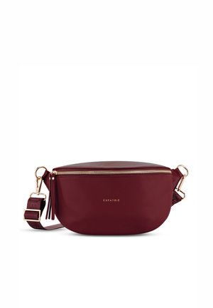 Sac bandoulière rouge foncé avec fermeture éclair dorée, large sangle réglable et petit logo doré "Expatrié" sur le devant.