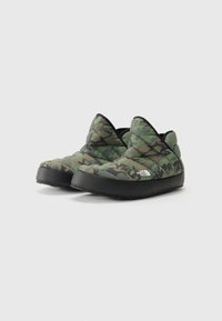 Utendørs slip-on sko i kamuflasjemønster. Polstret quilted overdel, svart gummisåle og svart piping rundt kantene.