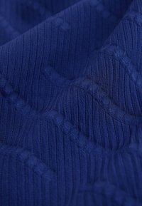 Tissu bleu texturé avec des côtes verticales et des motifs géométriques subtils créant de doux plis et ombres.