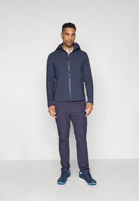 Navy hooded jacket with a front zipper and side pockets, paired with matching navy pants and blue athletic shoes. Smooth, lightweight fabric.