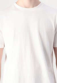 T-shirt bianco a maniche corte in cotone con scollatura rotonda e una superficie morbida, leggermente texturizzata. Presenta una vestibilità classica e rilassata.