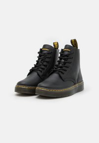 Black leather ankle boots with round toes, lace-up front, yellow stitching, and a yellow and black pull tab. Textured rubber sole.