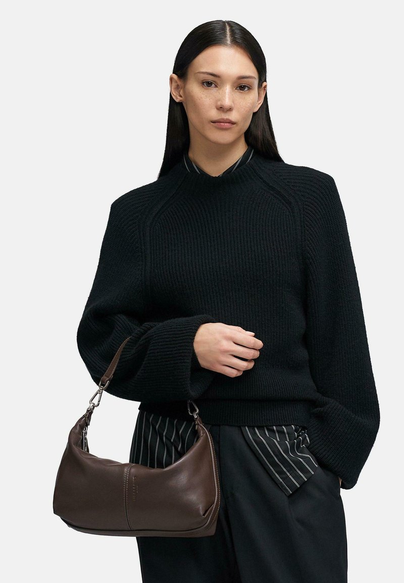 Brązowa skórzana torba na ramię o zakrzywionym kształcie i gładkiej fakturze. Posiada krótki uchwyt i subtelne przeszycia.