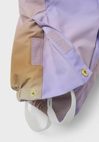 Paarse en bruine kleurgeblokte jasstof, voorzien van een klittenbandpatch, gouden drukknoopbevestigingen en elastische openingen voor een veilige pasvorm.