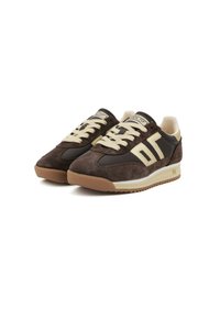 Zapatillas deportivas bajas en marrón y crema con paneles de ante, cordones cremosos y suelas de goma, mostrando detalles del logo en los laterales y en la lengüeta.