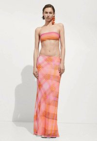 Ensemble deux pièces comprenant un top bandeau sans bretelles rose-orange et une longue jupe fluide avec un motif écossais coloré en rose, orange et marron.