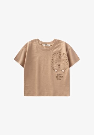 Beige t-paita lyhyillä hihoilla, valmistettu pehmeästä puuvillasta, jossa on pyöreä pääntie. Siinä on brodeerattu leijonakuvio, jossa lukee "VALMIS HAUSKAA PITÄMÄÄN."