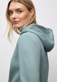 Felpa con cappuccio in morbido tessuto azzurro chiaro con una vestibilità comoda. Presenta un design semplice e cuciture pulite vicino al cappuccio e alle spalle.