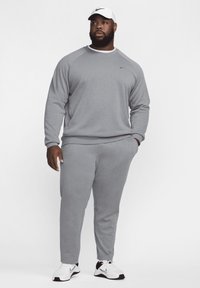 Szary sweatshirt i spodnie dresowe wykonane z mieszanki bawełny. Posiadają ściągacze przy mankietach i w pasie, a na piersi umieszczono małe czarne logo oraz czapkę.