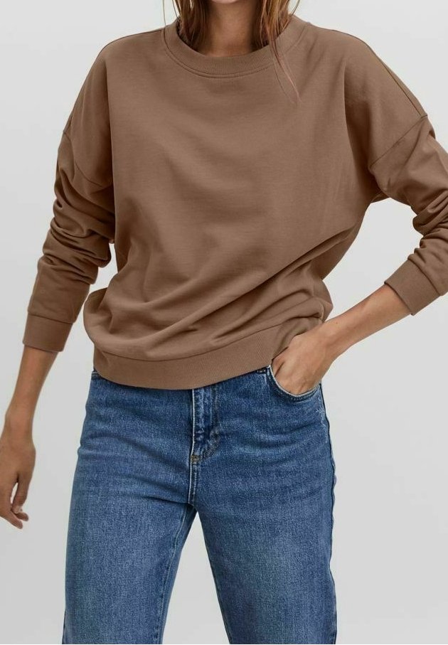 Hnědá nadměrná mikina s pokleslými rameny a žebrovanými manžetami, kombinovaná se světle modrými džínami. Hladká textura, volný střih.