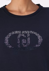 T-shirt blu navy con scollo tondo caratterizzato da un design decorato con strass in tonalità di viola e argento.