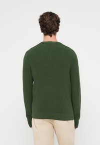 Zielony, dzianinowy sweter z długimi rękawami, prążkowaną fakturą i okrągłym dekoltem. Zaprojektowany w luźnym kroju, z prostym, gładkim tyłem.