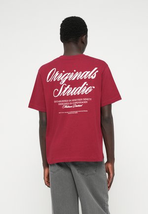 T-shirt de algodão cor burgundy com letras brancas nas costas, apresentando detalhes da marca e um corte descontraído, mangas curtas e gola redonda.