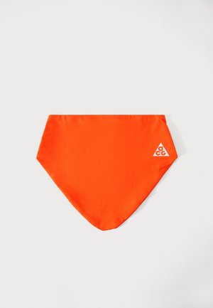 Lyse orange trekantet halsedisse med et lille hvidt trekantet logo markeret "acg" på den ene side mod en ensfarvet lys baggrund.