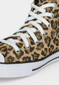 Αθλητικό παπούτσι τύπου high-top με λευκά κορδόνια, επάνω μέρος από καμβά με εκτύπωση λεοπάρδας σε ταμπά και μαύρο χρώμα και λευκή λαστιχένια σόλα.
