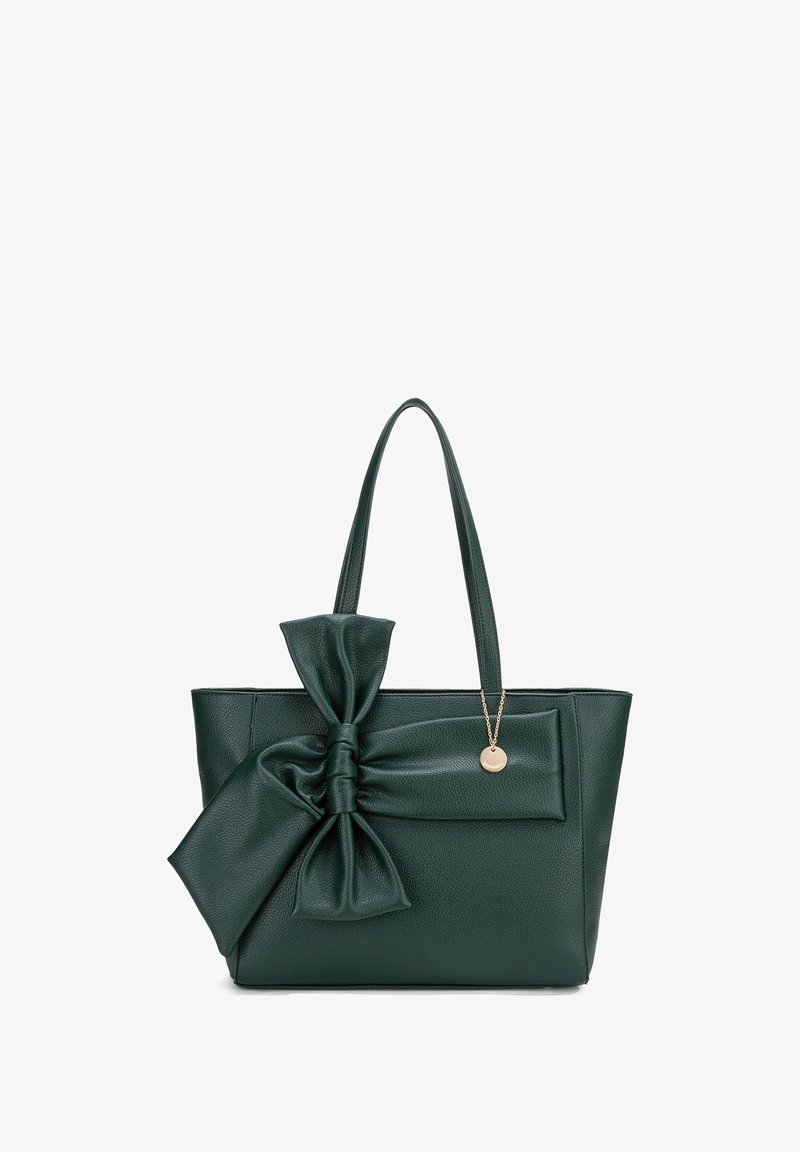 Borsa a spalla in pelle verde con un grande fiocco sulla parte anteriore, due manici e un ciondolo dorato, caratterizzata da una superficie texture e una forma rettangolare.