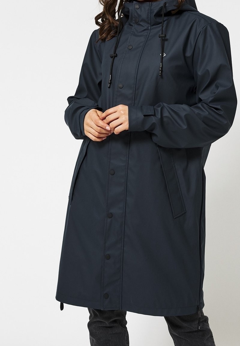 Mörkblå vattentät jacka med huva, långa ärmar, tryckknappar och dragsnören. Har sidfickor och en avslappnad passform.