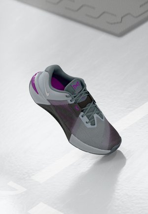 Modern gray and purple athletic sneaker with laces resting on a reflective white surface with faint markings.