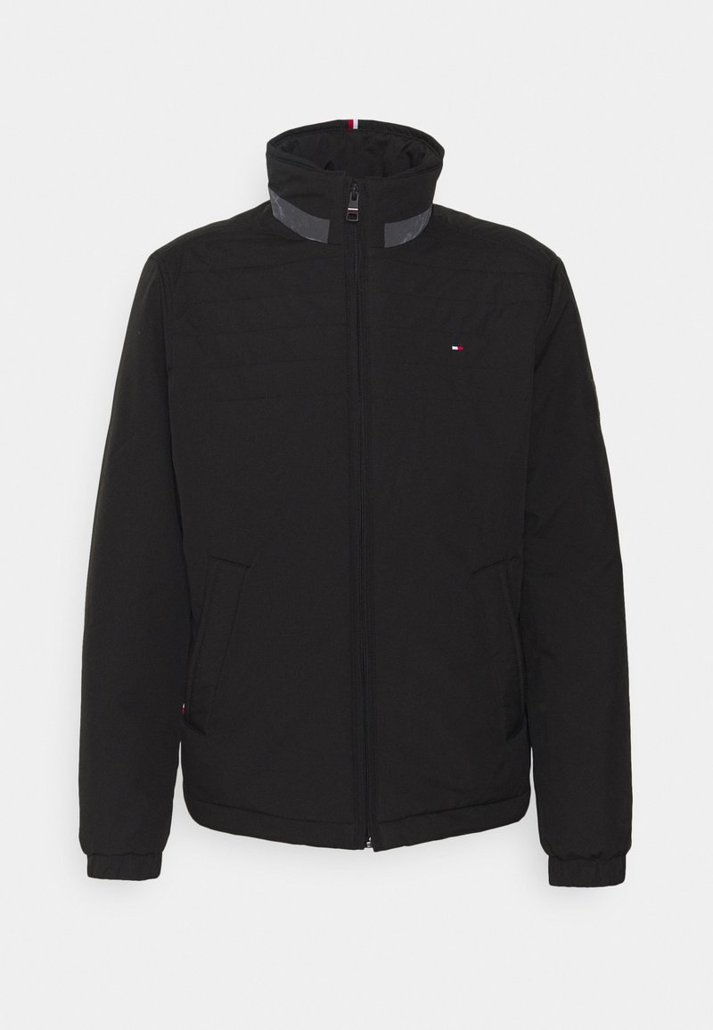 Veste noire zippée avec col montant, deux poches avant et petit logo rouge, blanc et bleu sur la poitrine et le col.