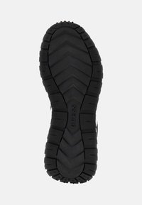 Suola di scarpa in gomma nera con un motivo di trazione a zigzag, caratterizzata da segmenti rialzati e il nome del marchio "GUESS" in rilievo al centro.