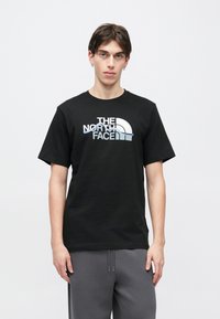 Μαύρο βαμβακερό T-shirt με κοντά μανίκια, με λευκό και ανοιχτό μπλε λογότυπο της "The North Face" στο στήθος.