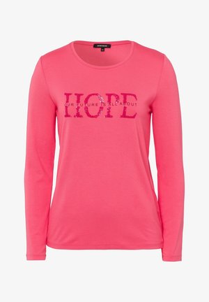 Różowa koszula z długim rękawem z okrągłym dekoltem, z cekinowym napisem "HOPE" i mniejszym napisem "OUR FUTURE IS ALL ABOUT" na wysokości klatki piersiowej.