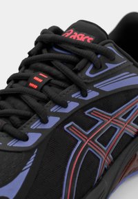 Asics teniske v črni mrežasti tkanini, s poudarki v modri in rdeči barvi, teksturiranimi vezalkami in oblikovanim podplatom z izrazitim dizajnom.
