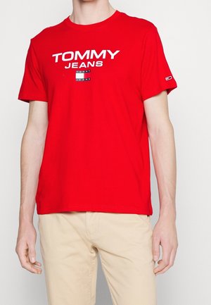 T-shirt rouge en coton à manches courtes. Sur le devant, le texte "TOMMY JEANS" en blanc et noir. Encolure ras-du-cou côtelée et coupe basique.