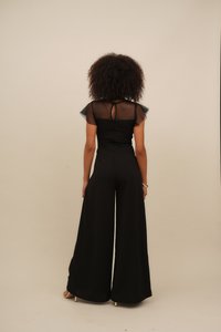 Black jumpsuit featuring sheer short sleeves, a keyhole back, and wide-leg trousers. Smooth texture with minimalistic design.