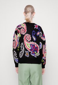 Pull noir en maille avec des motifs cachemire et floraux colorés. Il présente des manches longues ainsi qu'un col, des poignets et un ourlet côtelés.
