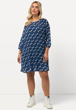 Navyblaues Kleid mit floralem Muster, plissiertem Design, rundem Ausschnitt und drei Viertel-Ärmeln, kombiniert mit weißen High-Top-Sneakern.
