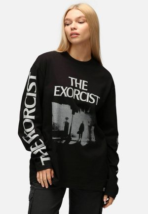 Black long-sleeve t-shirt featuring "The Exorcist" graphic in white and gray. Relaxed fit, with a bold print on front and sleeves.