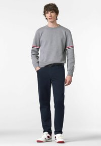 Grauer Pullover mit roten und weißen Streifen an den Ärmeln, marineblaue Hose und weiße Sneaker mit roten Akzenten. Lässiger Schnitt, gestrickte Textur und klassischer Kragen.