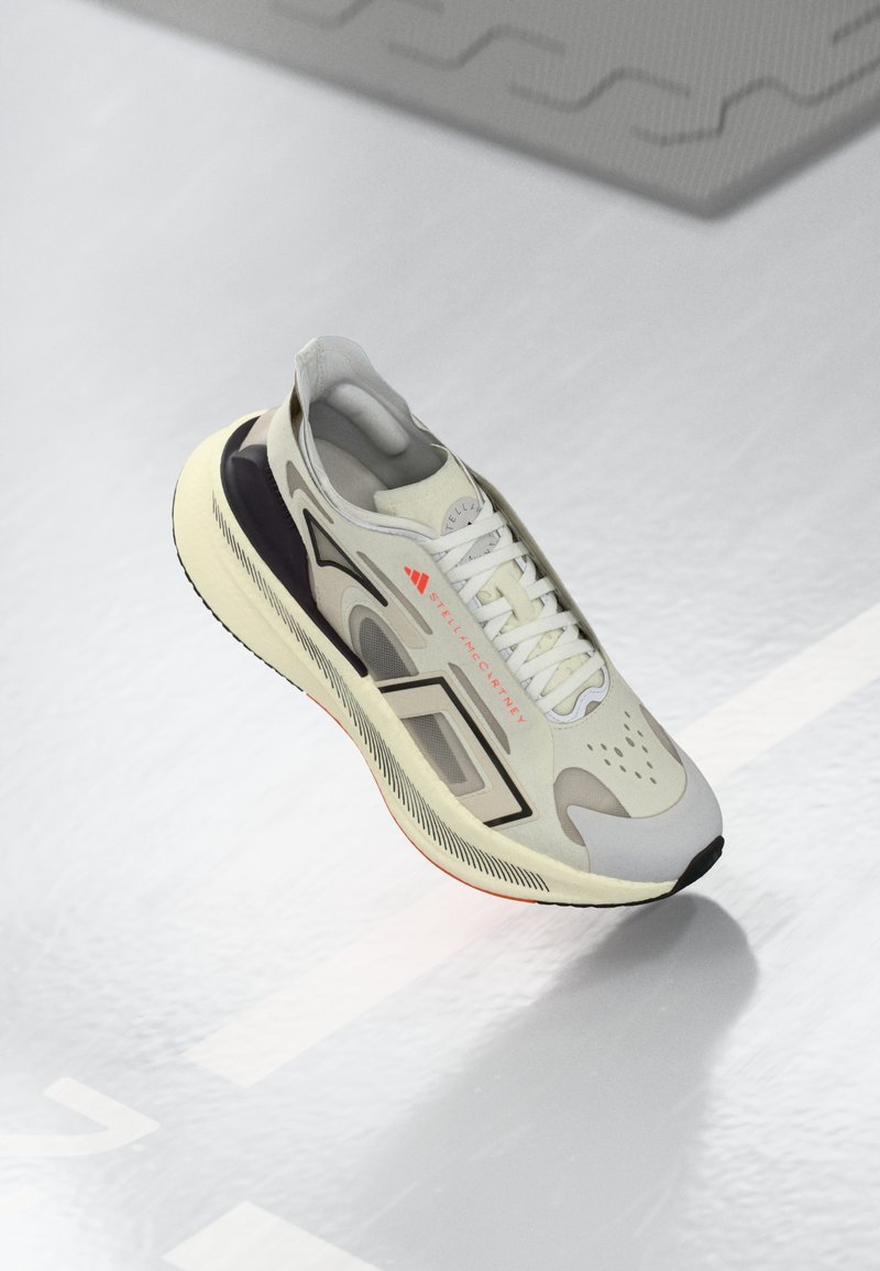 Beige ja must atletikajalats valgete paeltega, punase "Stella McCartney" brändimisega ja paksu pehmendusega tallaga peegeldaval pinnal.