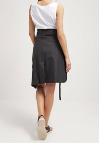 Svart randig midi kjol med hög midja och knytning i midjan. Har en texturerad tyg och når till mitten av vaderna.