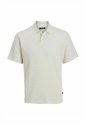 Lühikeste varrukatega polo särk kreemjas värvitoonis, tekstuurse kudumisega. Omab kaelust ja kolme nupuga nööpplaati. Diskreetne siksakiline mustriline.