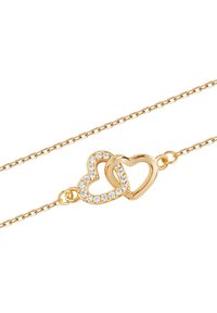 Złota bransoletka z łańcuszka z dwoma splatającymi się zawieszkami w kształcie serca, z których jedna ozdobiona jest przezroczystymi cyrkoniami, ma gładkie metaliczne wykończenie oraz delikatną teksturę.