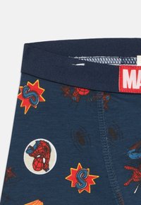 Mørkeblå bomuldsboxershorts med Spiderman-grafik, rød elastik med "MARVEL"-label og forskellige superhelte-motiver og mønstre.