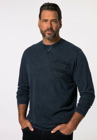 Granatowa bawełniana koszula z długimi rękawami i okrągłym dekoltem, z wytłoczonym napisem "LAKE AREA WYOMING" na klatce piersiowej. Miękka, teksturowana tkanina.