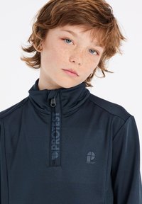 Marineblauwe kwart-rits pullover gemaakt van gladde stof. Heeft een hoge kraag, ritssluiting en een logo-accent aan de voorkant.