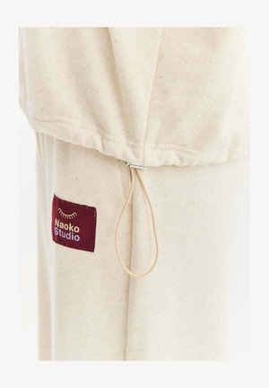 Bawełniany ubranie w kolorze kremowym z marszczonym dołem i regulowanym sznurkiem. Posiada bordową metkę z napisem "Naoko Studio".
