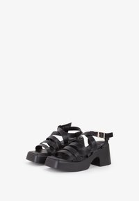 Sandali platform neri con un design a più cinghie, realizzati in materiale liscio. Presentano una cinghia alla caviglia con una fibbia dorata. Tacco spesso.