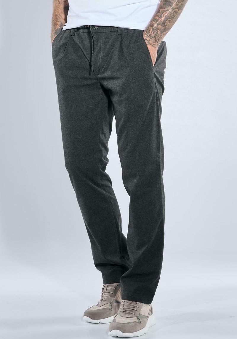 Dark gray trousers with a tailored fit, featuring pleats, side pockets, and a smooth texture, paired with light-colored sneakers.