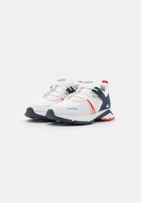 Sport shoes with a white mesh upper, navy and red accents, signature logo, elastic laces, and textured heel. Rubber sole for traction.