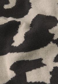 Tissu en tricot avec un motif abstrait noir et crème. Texture douce avec une légère élasticité et des blocs de couleur variés tout au long.